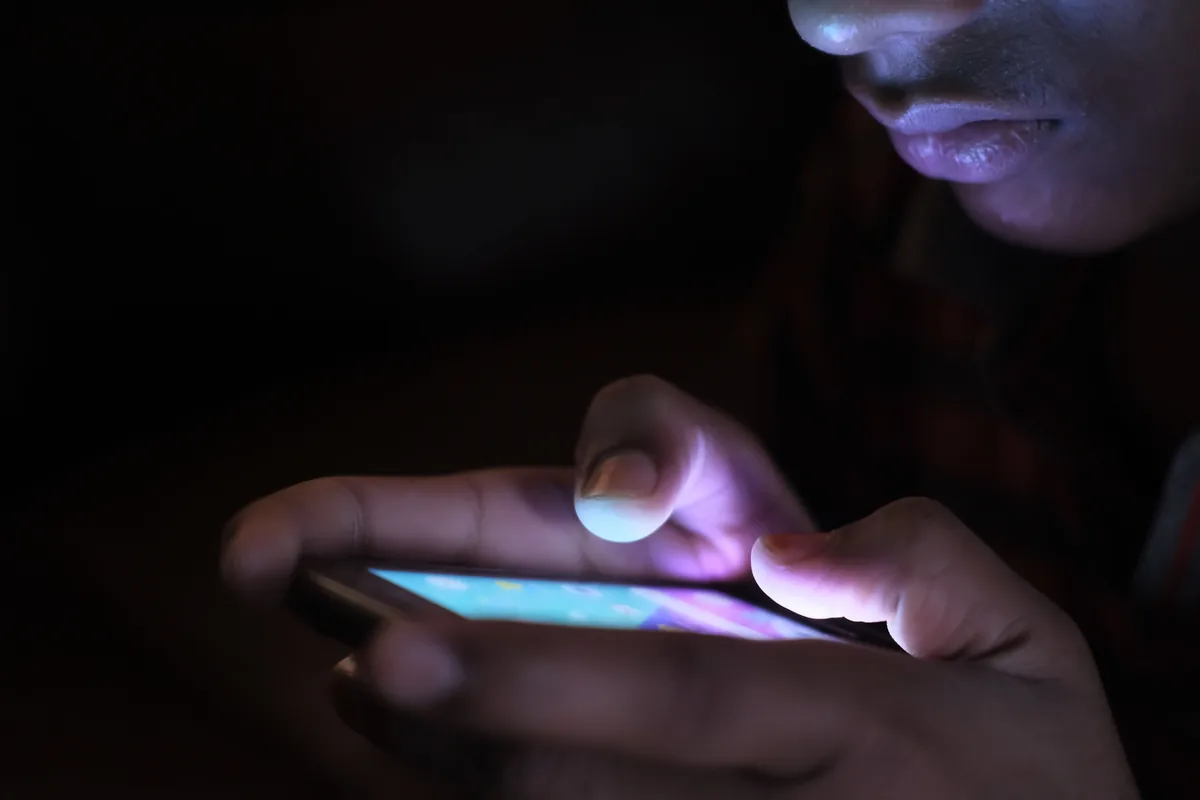 A face lit by a phone screen in the dark, illustrating late-night searches for emergency credit
